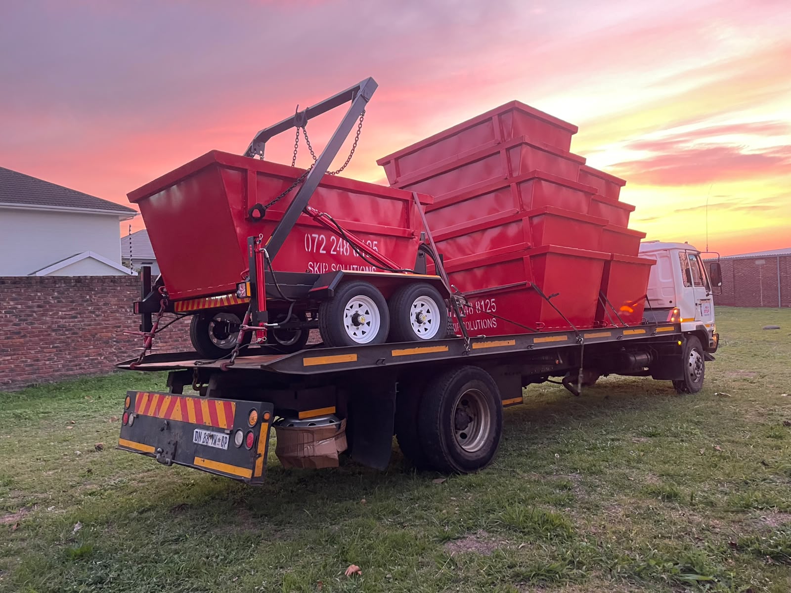 Skip Solutions red skips loaded on a truck for weekend hire